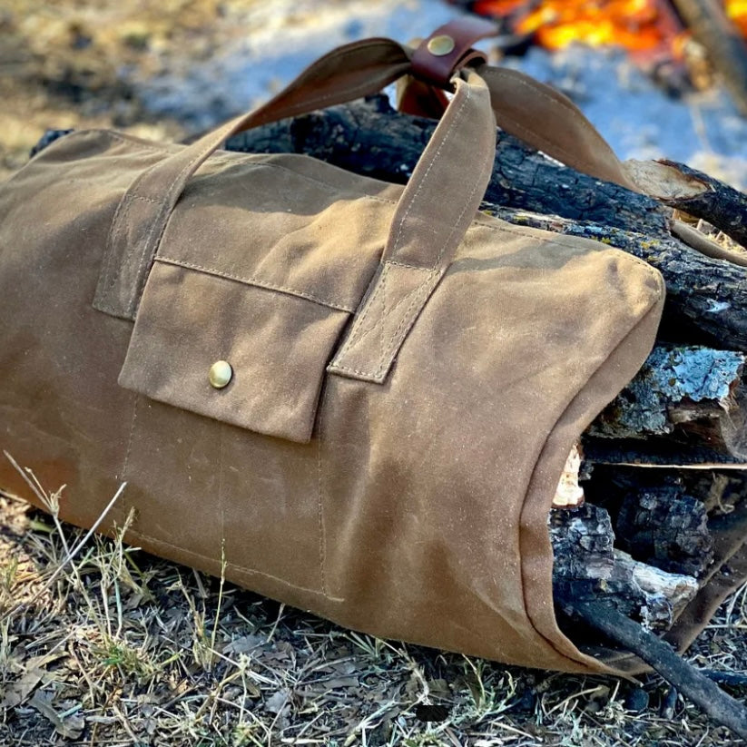 Forester Log Tote made of waxed canvas, carrying firewood, with pocket for supplies, ideal for camping.