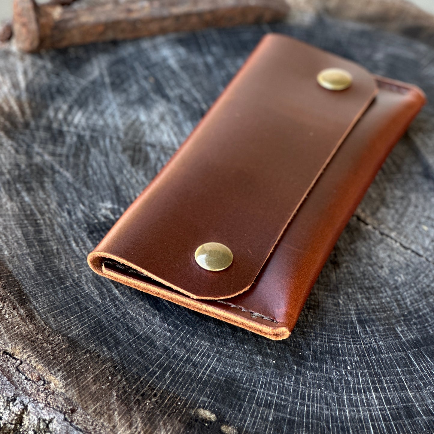 The 1690 Wallet in premium Oxford Xcel leather on a wooden surface, featuring brass snap closures.