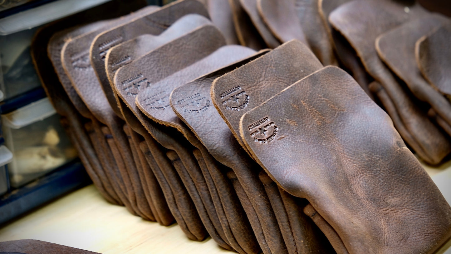 Row of small leather field pouches made from oil tanned hide, showcasing their rich texture and craftsmanship.