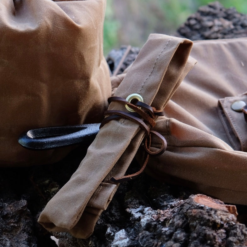 Close-up of a brown waxed canvas utensil pouch and rolled storage, showcasing quality design and materials.