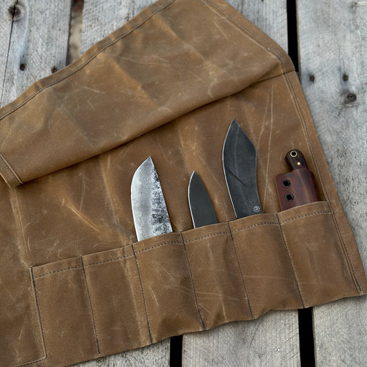 Waxed canvas knife roll with three knives and a tool, showcasing durable design and storage pockets.