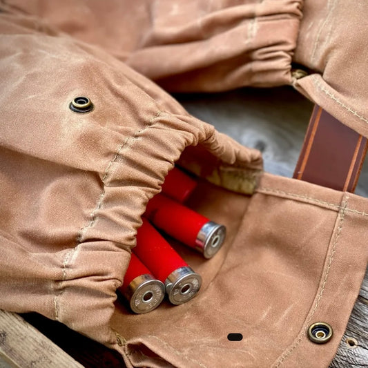 Close-up of a russet brown waxed canvas shotgun shell pouch with red shotgun shells inside.