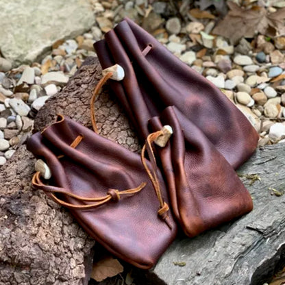 Handmade Voyageur leather drawstring pouches in rich brown, ideal for carrying personal items and goods.